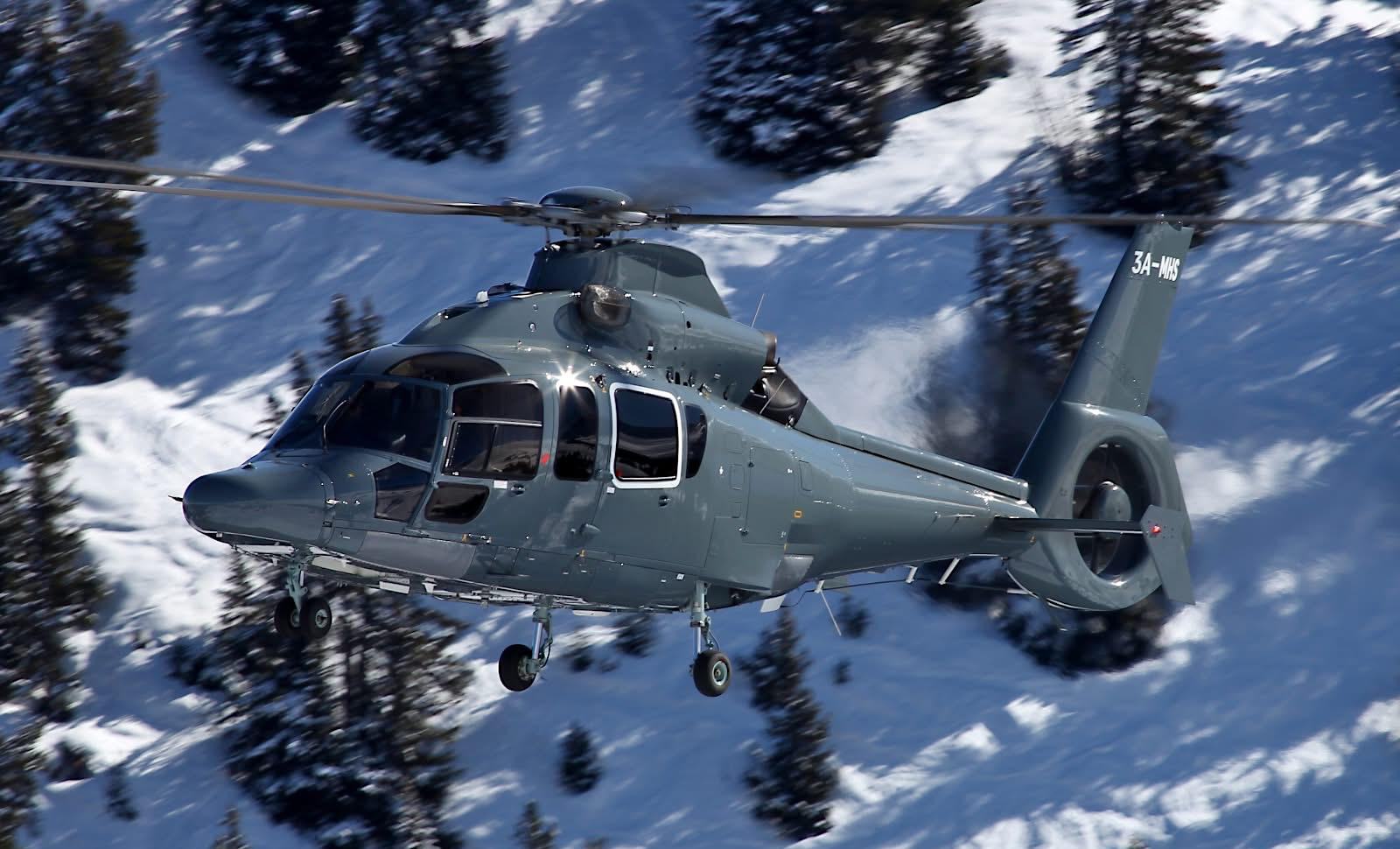 The managed helicopter in flight above a snow-covered alpine forest